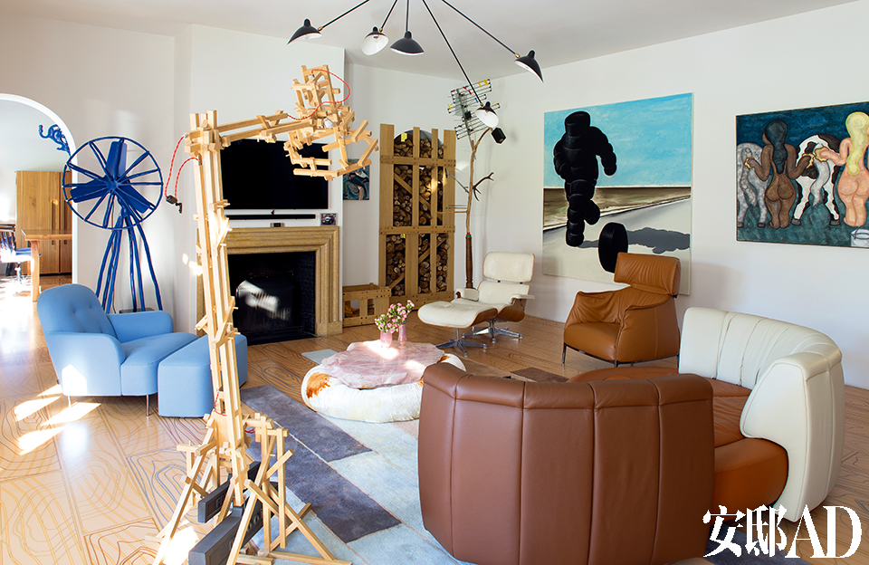 客厅里的黏土蓝色风扇由荷兰设计师Maarten Baas创作。天花板上的黑色金属吊灯是法国设计师Serge Mouille的作品。壁炉是建筑原有的。一旁的木质壁橱柜门出自Studio Makkink & Bey的设计。壁橱前是美国设计师Charles Eames著名的Lounge Chair座椅。右边墙上挂着波兰艺术家Wilhelm Sasnal的画作。