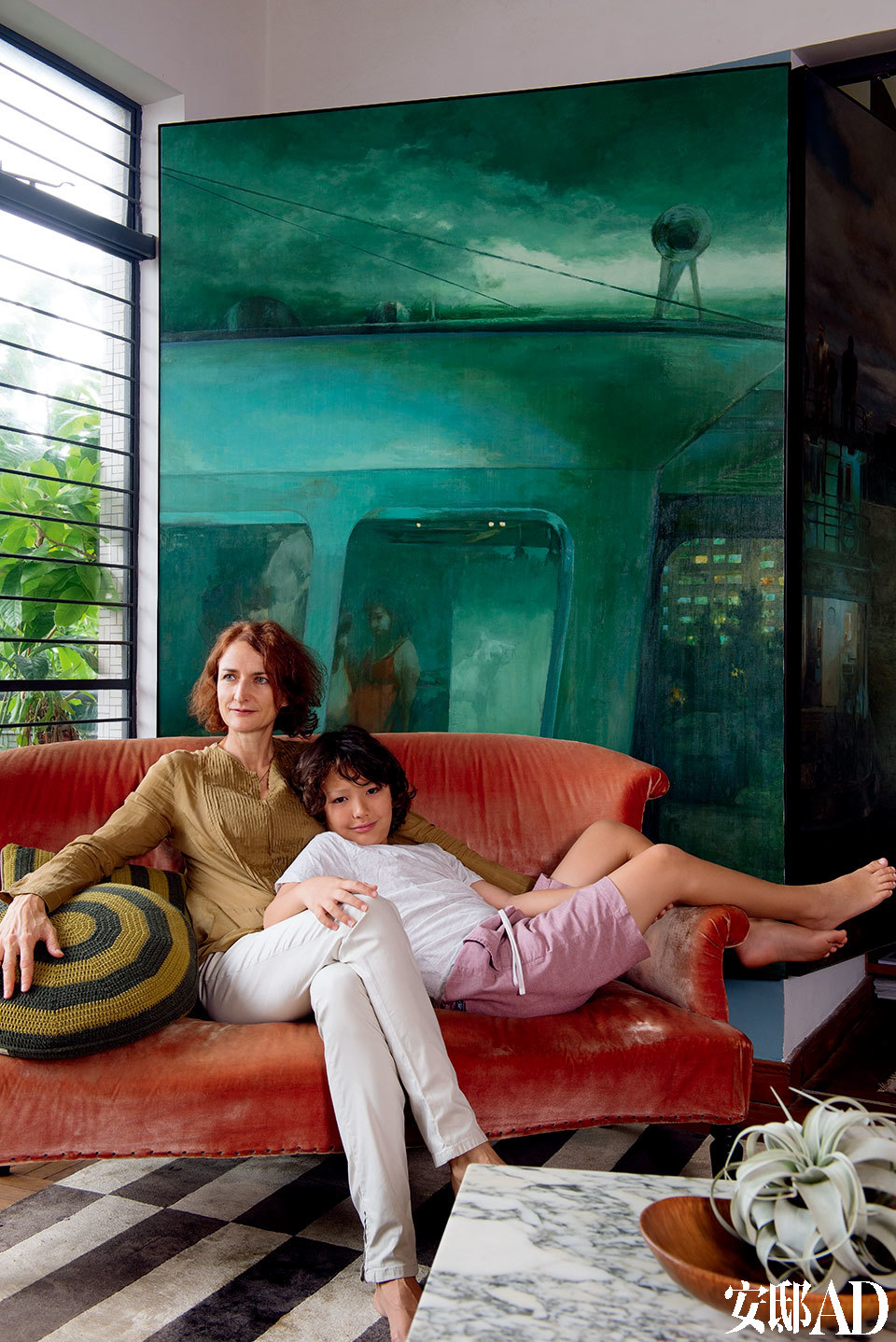 材质、款式以至出身地各异的沙发和椅子，是一家人的安乐“窝”。画家杨东龙描绘香港市貌的画作，呼应了墙身的绿调和窗外的绿荫，十分抢眼。购自巴黎跳蚤市集的1940年代橙红色丝绒沙发，她自言最爱窝在里面读报。主人：Debra Little，生于阿德莱德、后移居墨尔本的Debra，1991年应建筑公司之邀来到香港，参与机场、酒店和企业等设计项目，而后成立自己的设计顾问公司、开设独立设计品店DeeM，2011年开始经营艺廊“。当初并没想过投身艺术行列，就如同当年在香港留下来发展事业一样，一切只是随心而动。”