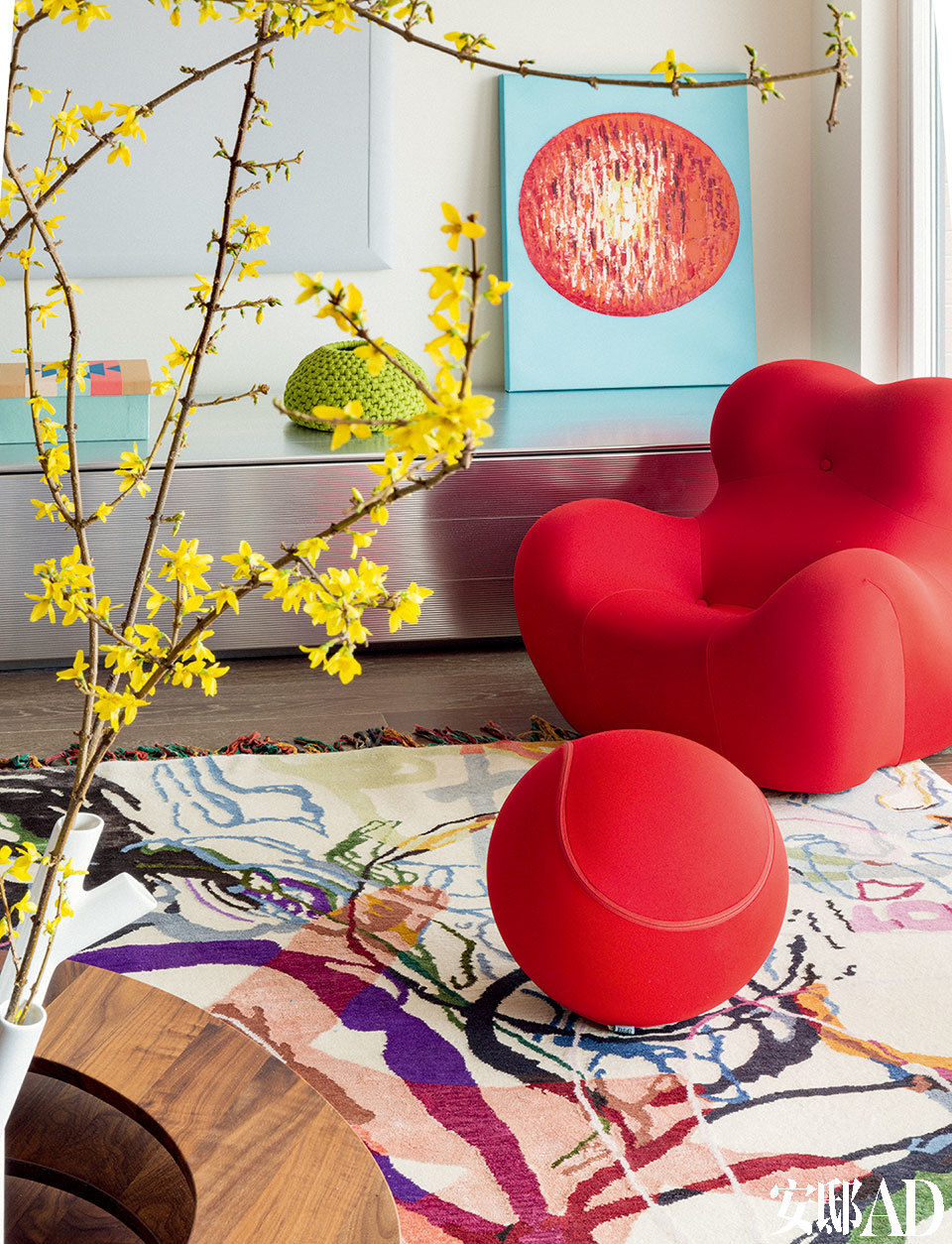 客廳的一角，紅色單人沙發及圓球腳凳由B&BItalia出品，后面的銀色儲藏柜是梅婷家中原有的家具，柜頂的綠色Paolaleti編織花瓶來自豐意德，一旁的小幅畫作則來自Bo Concept北歐風情。
