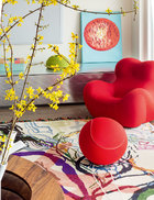 客廳的一角，紅色單人沙發及圓球腳凳由B&BItalia出品，后面的銀色儲藏柜是梅婷家中原有的家具，柜頂的綠色Paolaleti編織花瓶來自豐意德，一旁的小幅畫作則來自Bo Concept北歐風情。