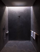 这间浴室由混凝土打造，在从顶部透来自然光下散发出神秘气息，龙头来自Fantini品牌。
