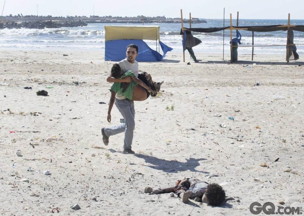 10.	今年夏天，巴以边境，加沙地带遭到以色列空袭，图中是袭击中死亡的男孩。受害者是渔夫的堂兄弟，虽然被警告不要外出，但还是没能逃离厄运。一个人抱着一名受害者，另一位受害者躺在他们前面，脸冲地埋在沙子里，腿已被炸断，这场冲突的残酷表露无遗。摄影师：泰勒-希克斯（纽约时报）