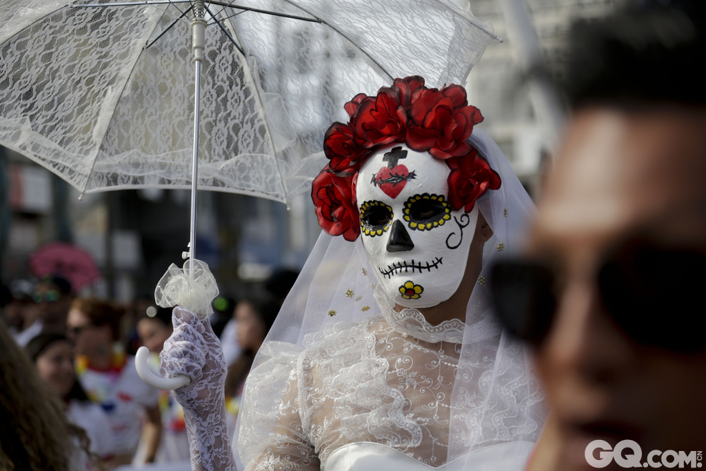 在巴拿马城，一名身穿婚纱和白色面具的男子拿着遮阳伞参加游行，表达了对同性恋合法婚姻的支持。