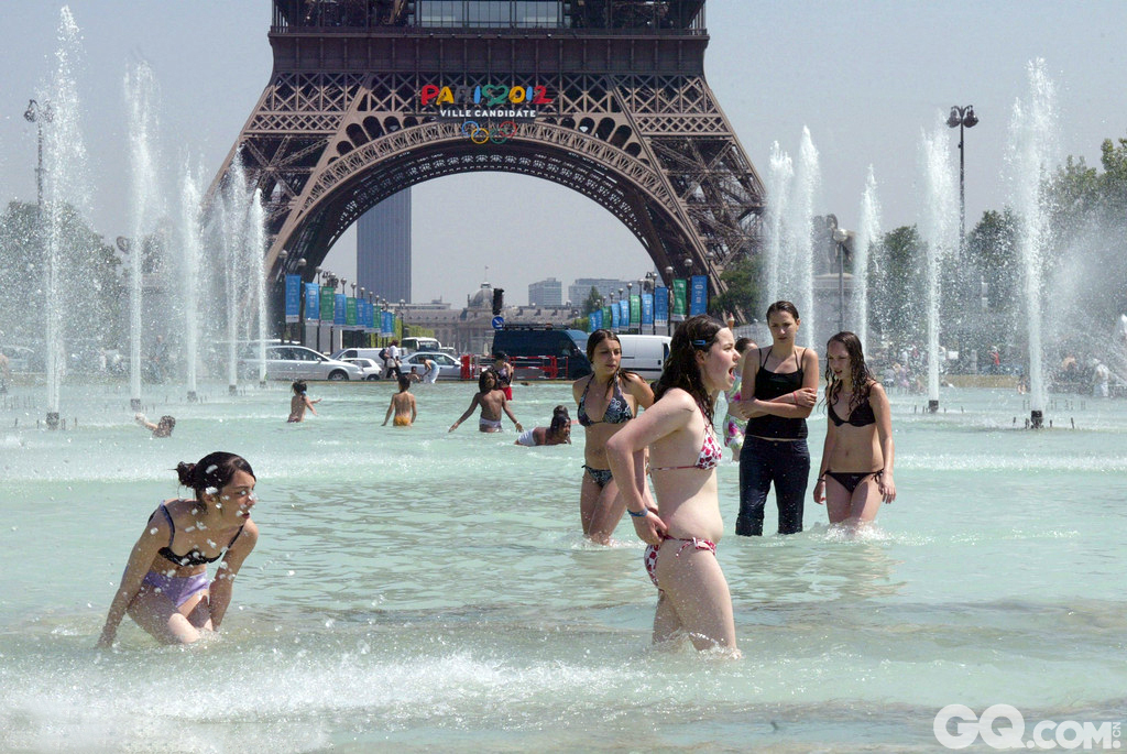 夏日炎炎，法国巴黎民众在埃菲尔铁塔前的喷泉中沐浴消暑或游泳。   