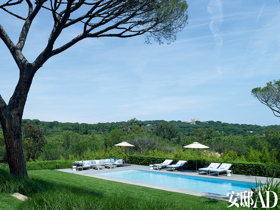 如果你有幸从飞机上俯瞰法国南部，会见到一座座蓝色泳池如宝石般镶嵌在绿色的丘陵和平地上，这里便是其中的一座了。郁郁葱葱的草坪和灌木包裹着澄澈发蓝的池水，池边的沙滩躺椅和户外休闲家具主要来自Roda品牌，最左侧的白色小凳子来自Gervasoni。