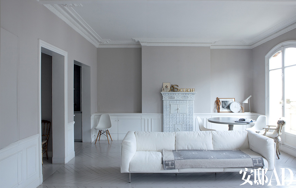 灰色和白色是女主人的最爱，也是这个家最本真的色彩。家具被减到最少，留下的几件18世纪瑞典风格古董椅则是多年来大浪淘沙的结晶。Sylvie尽量解放了原本被隔成多个卧室的空间，而得到这个宽敞的大客厅。为保存房子原有的橡木地板和踢脚线，整个房间都被刷成了灰色和白色相接的墙面。灰色墙面来自Flamant的
“Stone”系列。房间里还有出自
Piero Lissoni的“Rod”可拆换布
罩长沙发（Living Divani），沙发
上的灰色毛毯来自爱马仕，出自
Charles和Ray Eames的“DSW”
椅子（Vitra）以及18世纪的瑞典
古董椅都是Sylvie的个人收藏。
墙柜上摆放着David Seidner的
照片、由Leff Amsterdam发行
的纯白色时钟以及出自Arne
Jacobsen的“AJ”台灯（Louis
Poulsen）都为这个简约风格的
家增添了丰富层次。