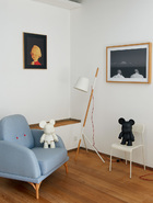 楼上卧室区，单人扶手沙发来自本土设计师品牌“吱音”， 落地灯是北欧设计师的作品，购自德国。左侧的画作是刘野的《小小莫扎特》，右侧的摄影作品来自高鸣。
