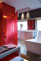 超现代的浴室里雕塑般的浴缸、面盆及水管都出自Antonio Lupi 为Tuscany设计的卫浴系列。红色马桶间的门把手由Philip Watts设计。开放式卫浴就嵌在卧室里面，浴缸与洗手盆仿佛两件雕塑，为空间添色不少。