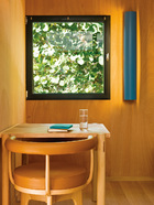黑框方窗是设计的一大特色，画框般将满目绿意引入室内。桌子旁边是夏洛特设计的LC7摇椅的木质凳脚独家版本。
