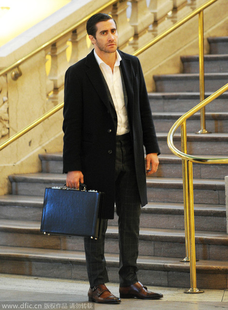 美国纽约当地时间2014年10月27日，杰克-吉伦哈尔（Jake Gyllenhaal）曝光了《爆破》片场的造型。白衬衫与格纹裤组合，没有领带和裤带的束缚凸显舒适感。硬质公文包和僧侣搭扣鞋平添绅士质感。再外搭一件器宇不凡的两粒扣中长款黑风衣。如此讲究的戏服让人对这部片子还有点小期待呢！